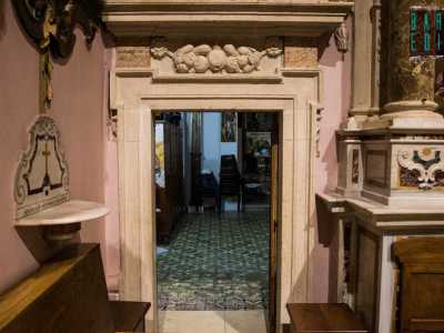 Ai lati si aprono poi due porticine speculari dalla trabeazione lineare interrotta solo dalle sculture di melograni, simbolo di vita e rinascita: sono i due accessi alla sagrestia